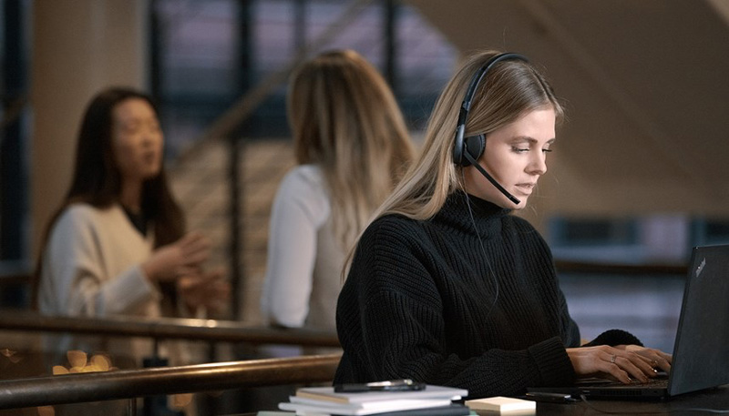 Woman wearing wired headset at laptop